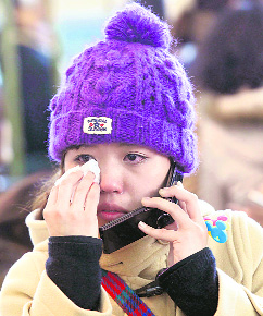 A Japanese traveller wipes tears as she talks over the telephone at an airport in west of Seoul on Friday.