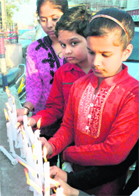 Children pray for the earthquake victims of Japan by lighting candles at Committee Chowk in Karnal on Saturday. 
