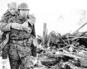 A soldier carries an elderly man to a shelter in Natori city, Miyagi prefecture