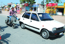 A scooterist tries to push a car after it broke down on the Powerhouse road in Bathinda