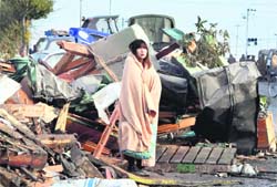 A girl, wrapped in a blanket, looks at her surroundings in the tsunami ravaged town of Ishinomaki city in Miyagi prefecture on Sunday