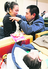 A man reacts as he finds his wife and child at a Red Cross hospital after they were separated by an earthquake, in Ishinomaki on Monday.