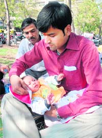 A dejected Sandeep, who came from Muzaffarnagar in Uttar Pradesh, cradles Nishtha, his four-month-old baby girl, in the lawns outside the Advanced Paediatric Centre at the PGI