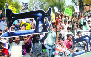 Garment manufacturers shout slogans during a protest, demanding the withdrawal of excise duty on branded clothes at Jantar Mantar in New Delhi on Tuesday.