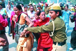 A woman constable whisks away AIE Teachers Union activists after they staged protest near the Sirhind canal on Wednesday