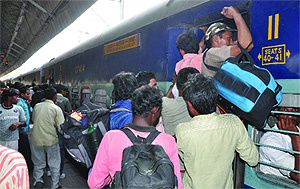 Passengers struggle to get into a moving train at New Delhi railway station to reach home for the festival of colours on Friday. 