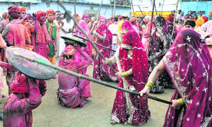 Men try to protect themselves with bucklers as women beat them up with sticks during Lathmaar Holi celebrations in Nandgaon village of Mathura.