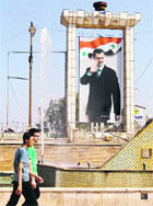 Syrian youths walk past a portrait of Syrian President Bashar al-Assad in Daraa. 