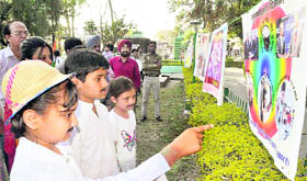 Three students look at a poster during an exhibition on the martyrdom day of Bhagat Singh, Rajguru and Sukhdev at the Gandhi Park in Dehradun on Wednesday. 