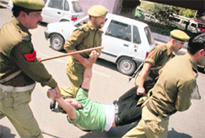 Policemen detain a protesting agriculture technocrat during a rally in Jammu on Thursday