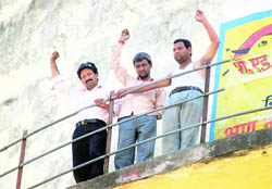Unemployed teachers wave from atop a water tank at Banu School in Dehradun on Sunday. 