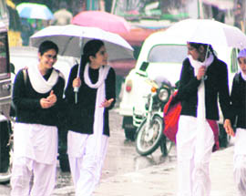 Schoolgirls walk with umbrellas in rain in Srinagar on Monday.
