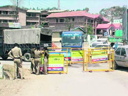 Police personnel stand guard at the venue for the auction of liquor vends in Pitthoragarh on Tuesday.