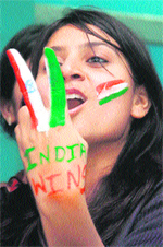 A young girl with the Indian Tricolour painted on her face shows the victory sign