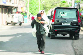 A man carries an old woman on his shoulders near the Government Hospital in Gandhi Nagar, Jammu.
