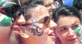 Cricket fans with their faces painted cheer for Team India outside the stadium.