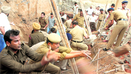 Police and fire brigade personnel clear the debris at the site of the wall cave-in at Industrial Area in Chandigarh on Thursday.