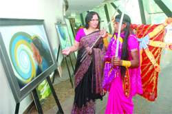 A tribal dancer from Jharkhand listens as painter Sandhya Singh explains her canvas work titled 'Hope for the Marginalized' at the national tribal mahasabha at Talkatora Indoor Stadium in New Delhi on Friday
