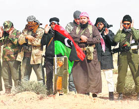 Rebel fighters pray at the grave of fellow rebels who were killed in a coalition airstrike on the road between Ajdabiyah and Brega on Saturday.