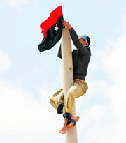 A rebel fixes a Kingdom of Libya flag on an electricity pole alongside a road to the east of Brega in Libya on Sunday.