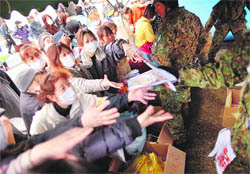 Tsunami victims reach for clothes distributed by members of the Self-Defence Force at a shelter for evacuees at Otsuchi in Japan on Sunday.