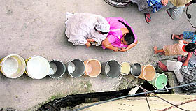 People await their turn to get water from a tap in the street in Patiala on Tuesday.