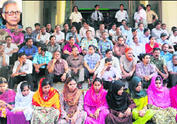 They banked on him: Employees of Grameen Bank gather in front of the office after Muhammad Yunus lost a final appeal against his sacking, in Dhaka