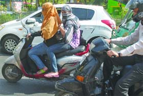 Girls cover their faces as they drive in New Delhi