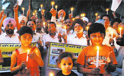 Under the banner of the Clapping and Laughing Club, residents hold a candlelight vigil to extend support to social activist Anna Hazare, at the Rose Garden in Bathinda