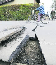 A cyclist passes by a road damaged by an earthquake in Kurihara, northern Japan, on Friday.