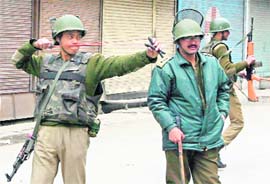 A paramilitary jawan tries to use a slingshot at Kashmiri protesters