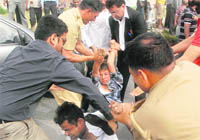The girls father (in black coat), along with policemen and passersby, catch hold of the youth.