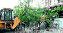 A bulldozer removes encroachments in Nehru Colony in Dehradun on Monday.