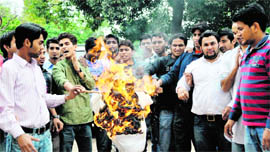 Students of DAV PG College burn an effigy of the Registrar, HNB Garhwal University, in Dehradun on Monday.