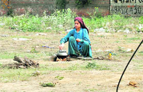 A homeless woman prepares food along a road in Gurgaon. 