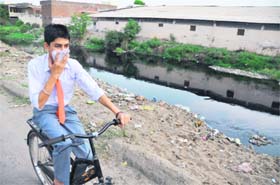 PERVADING STENCH: A boy covers his nose on his way to school near Kundan Puri