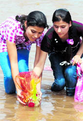 Devotees immersing Saankh, holy grass, in the Tawi on the occasion of Ramnaumi in Jammu on Tuesday