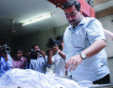 Vipin Behl with the body of his sister Anuradha at a mortuary in Noida on Wednesday. 