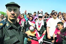 An Egyptian policeman stands guard as protesters shout slogans against ousted president Hosni Mubarak outside the Sharm el-Sheikh on Wednesday