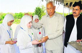 Governor NN Vohra presents a gift to a school student at Raj Bhawan in Jammu on Thursday