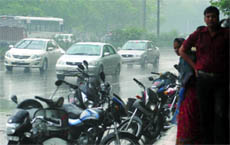Motorcyclists stand at a bus stop during the downpour in New Delhi on Sunday.