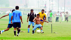 People play football at the India Gate Lawns during the morning rain.