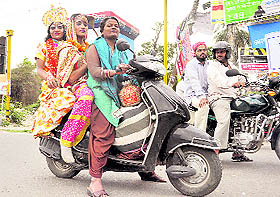Two artistes, riding a two wheeler, fully decked up to participate in a religious function in Dehradun on Sunday.