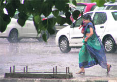 A woman carrying her child runs for cover after rain lashed Ludhiana on Sunday