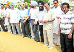 Officials led by Sangrur Deputy Commissioner Kumar Rahul inspect a heap of wheat at the grain market in Ahmedgarh on Sunday