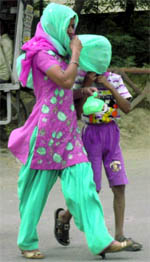 A woman protects her son during a storm in Patiala on Sunday