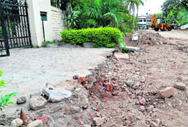Unfinished work on the pavement outside a house in Sector 34 hinders the passage of inhabitants and the damaged grill of a park in the same sector