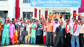 Shiksha Acharyas hold a demonstration in support of their demands in front of the Directorate, School Education, in Dehradun on Monday.