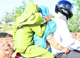 A man travels with two women on his bike as the temperature rises in Gurgaon.
