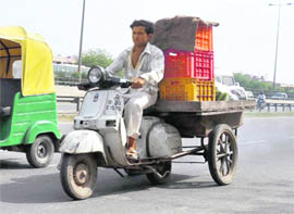 A vendor carries vegetables on his modified scooter 